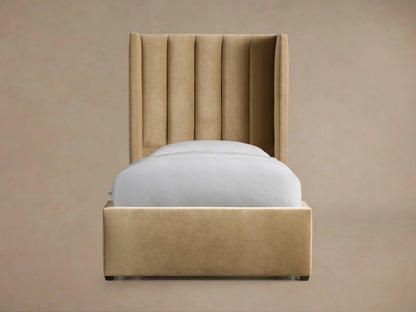 Tan Wyller Channel-Stitched Twin Bed with a tall, winged upholstered headboard, frame, and white bedding on a wood floor.