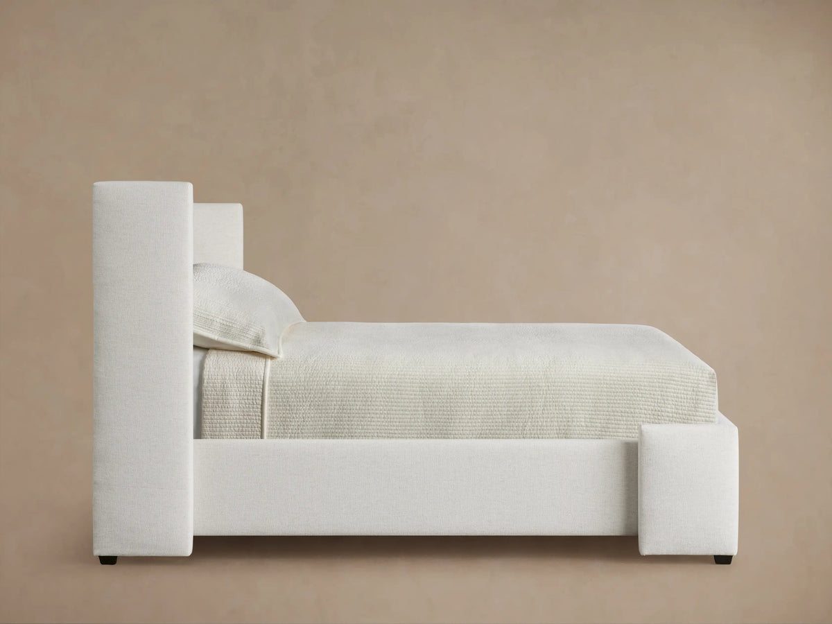 Close-up of the Wyller Channel-Stitched Twin Bed headboard, showing its plush, light cream, textured fabric with vertical channel stitching.