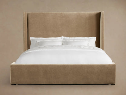 Wyller Bed with a tall, light brown upholstered wingback headboard and matching frame, dressed with crisp white bedding.