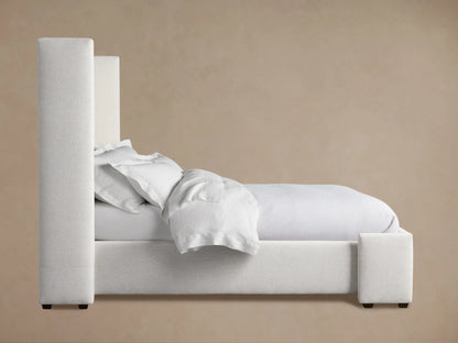 Close-up of Wyller Bed headboard, upholstered in light grey textured fabric, showing the clean lines and a subtle side wing.