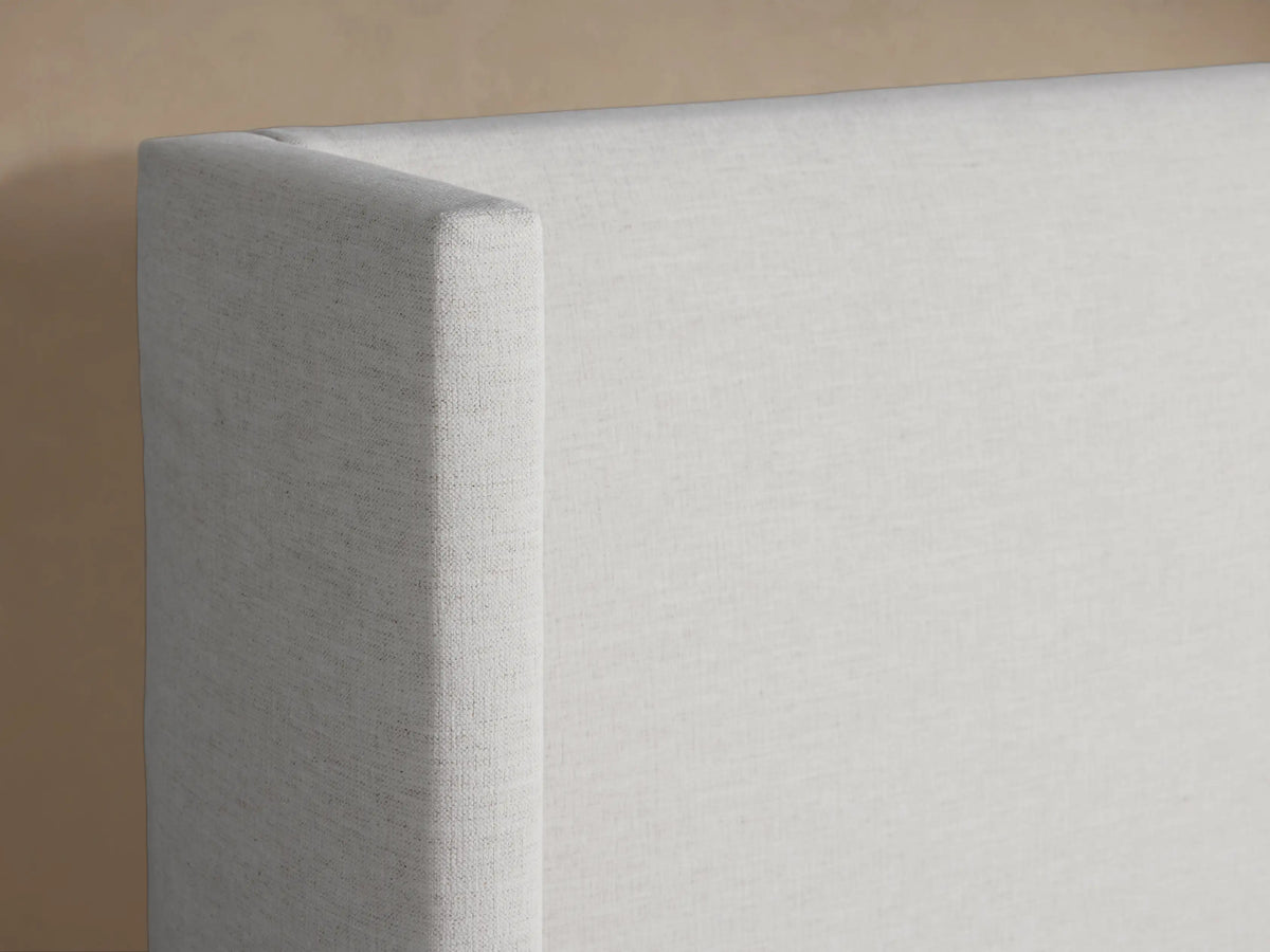 Wyller Bed: White upholstered bed, featuring a tall wingback headboard and platform base, dressed with white bedding, frontal view.