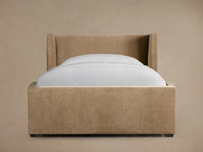 Wyller Twin Bed with light brown upholstered wingback headboard & frame, white mattress & bedding, on a dark wood floor.