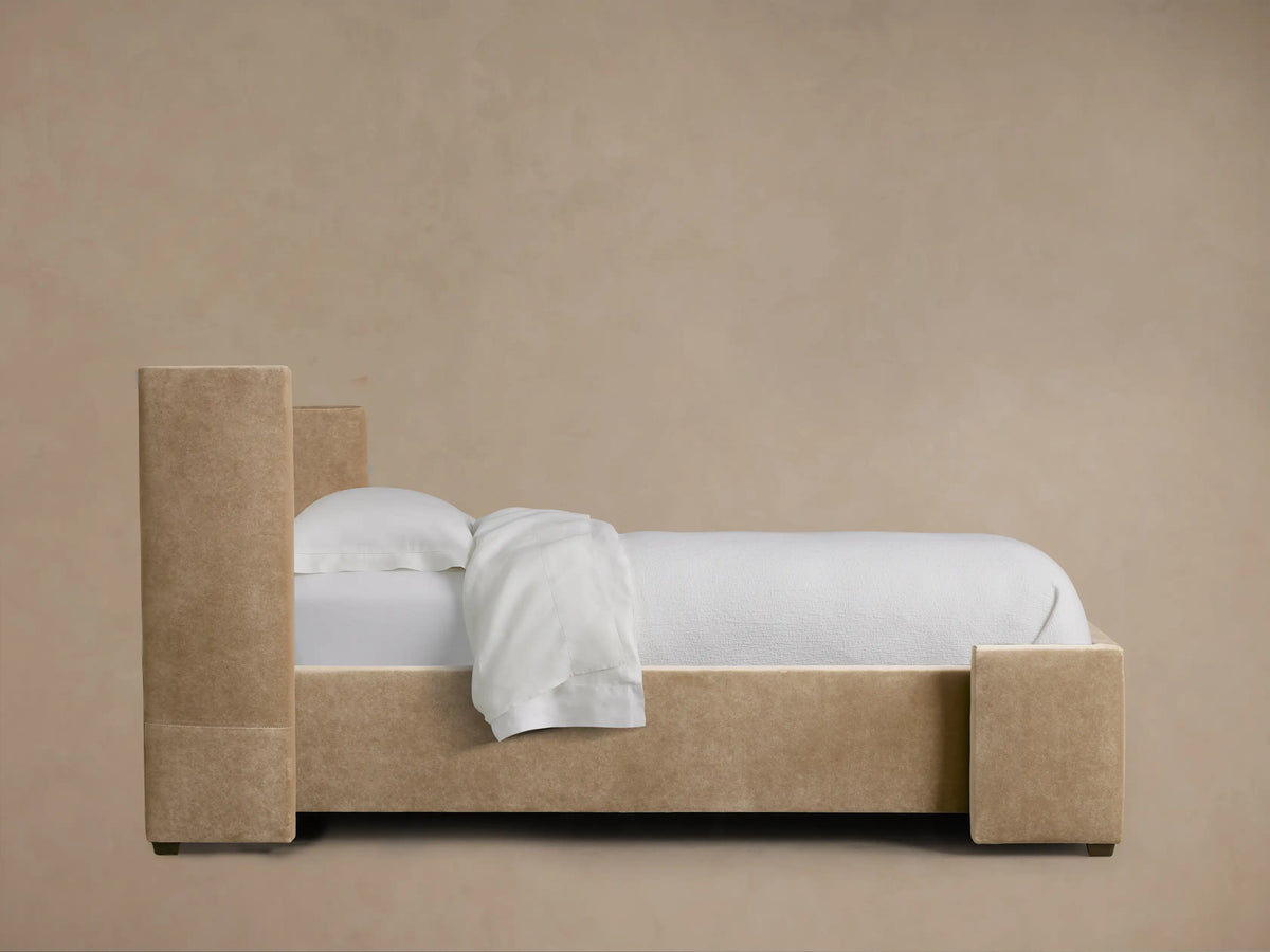 Wyller Twin Bed: Close-up of warm beige upholstered headboard corner, showing plush fabric and neat stitching.