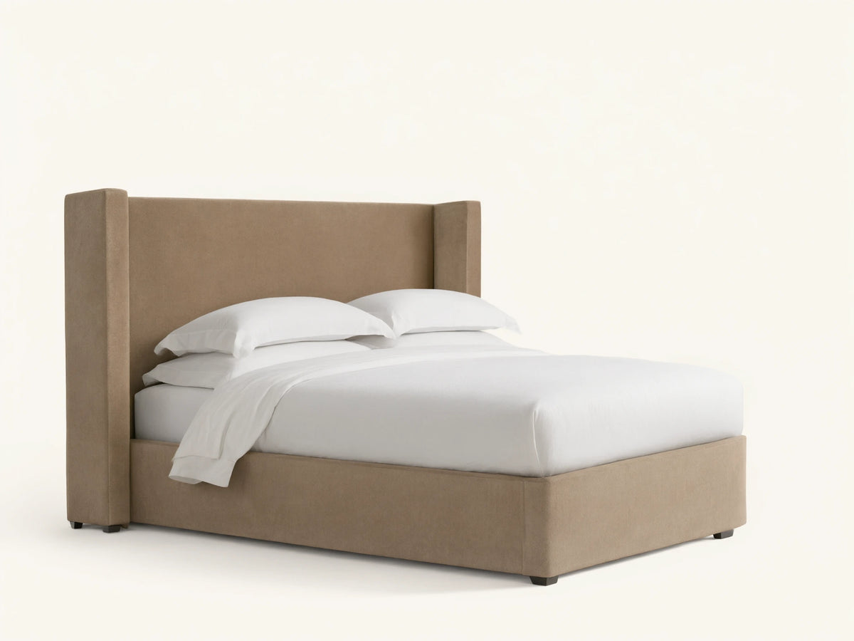 Wyller Twin Bed with light brown upholstered wingback headboard & frame, white mattress & bedding, on a dark wood floor.