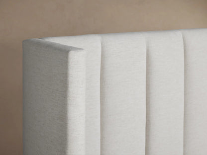 White Wyller Channel-Stitched Extended Headboard Bed with low footboard, centered against a beige wall, dressed with white bedding.