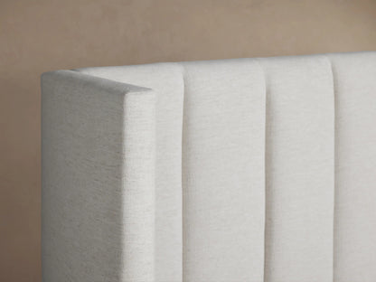Wyller Extended Headboard Bed. Light fabric bed featuring a channel-stitched extended headboard and low footboard, with white bedding.