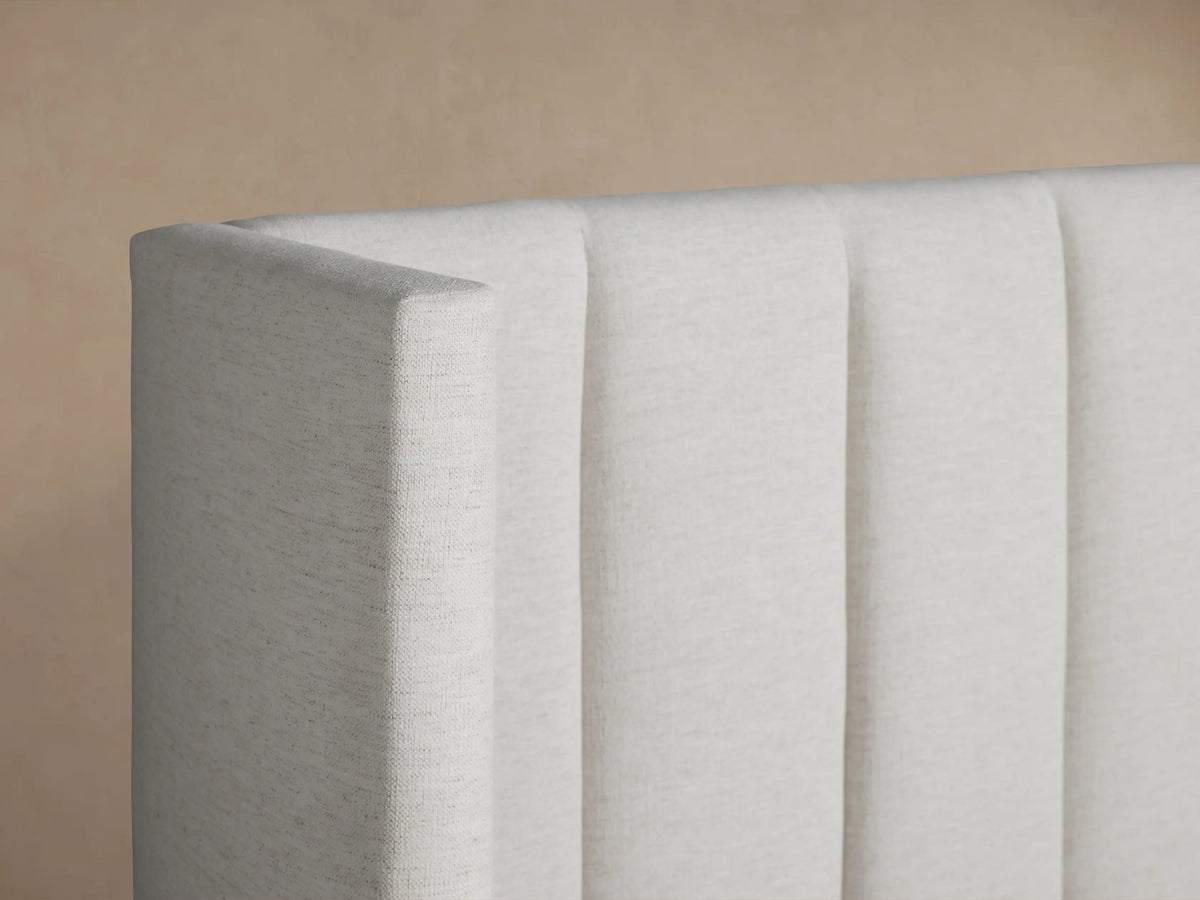 Wyller Channel-Stitched Bed with extended white upholstered headboard, vertical stitching, low footboard & white bedding.