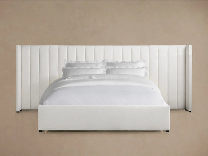 Wyller white channel-stitched extended headboard bed with a low footboard, dressed in white bedding, on a wooden floor.