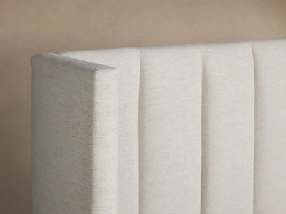 White Wyller Channel-Stitched Extended Headboard Bed with Low Footboard, made up with white bedding against a beige wall.