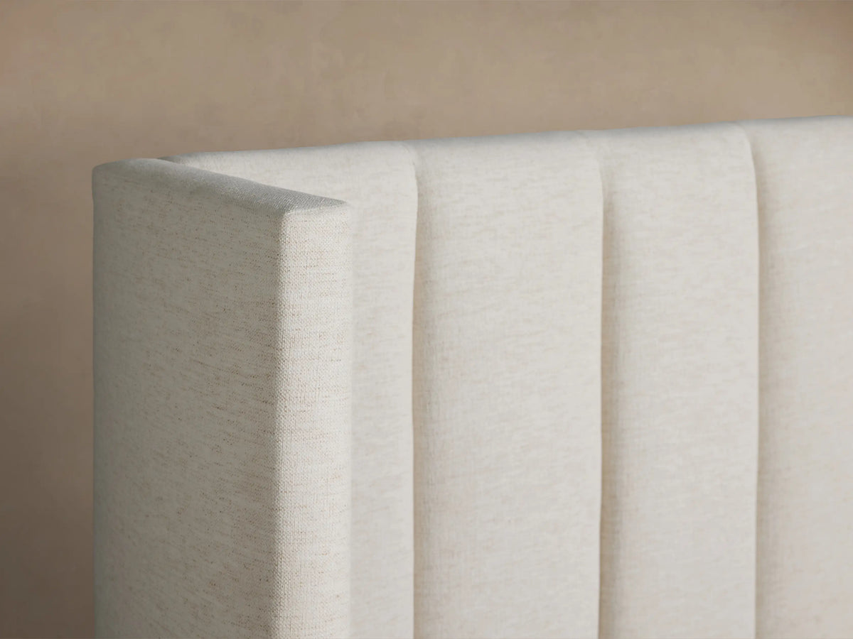 White Wyller Channel-Stitched Extended Headboard Bed with low footboard and white bedding, against a plain beige wall.