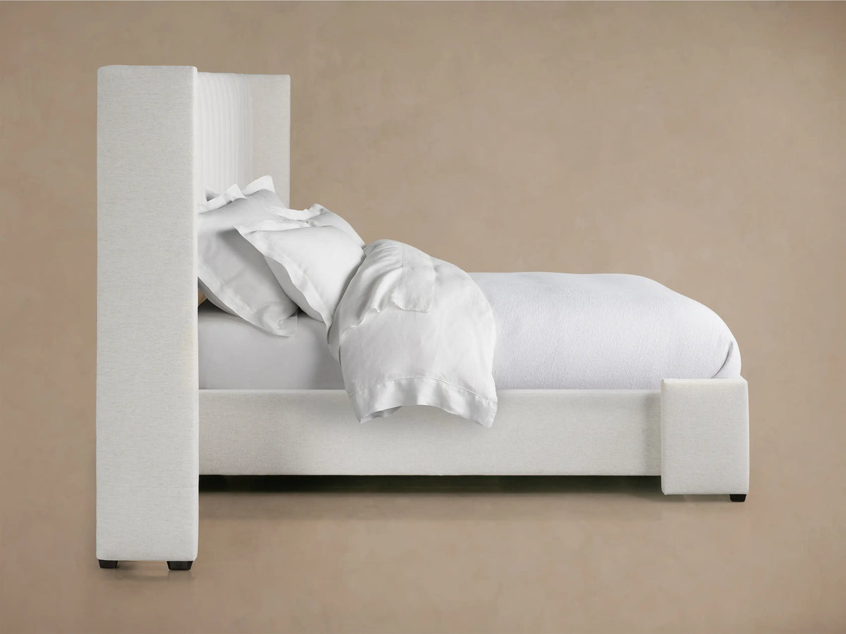 Close-up of Wyller channel-stitched headboard, light textured fabric, showing corner and vertical upholstered channels.