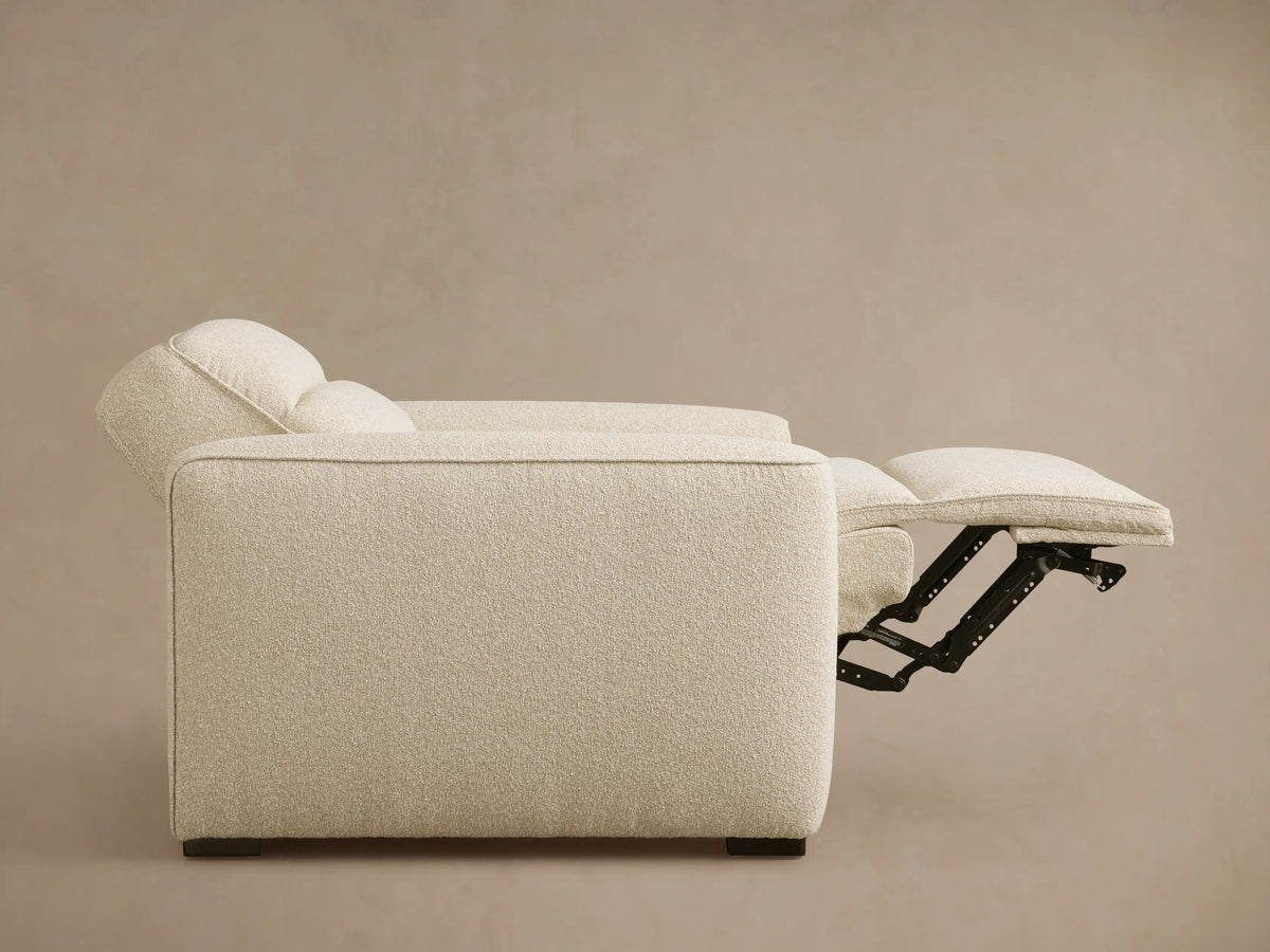 Front-side view of a cream Borough Motion Recliner with wide arms, padded back, and extended footrest.