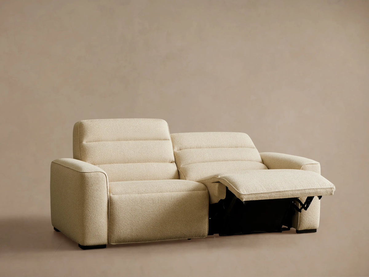 Front view of a light beige Borough Two-Piece Motion Sofa with the left footrest extended.