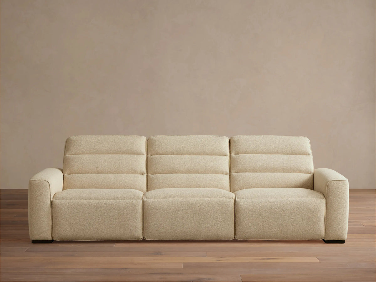 Front view of the light cream Borough Three-Piece Motion Sofa with horizontal stitched backrests and block arms.