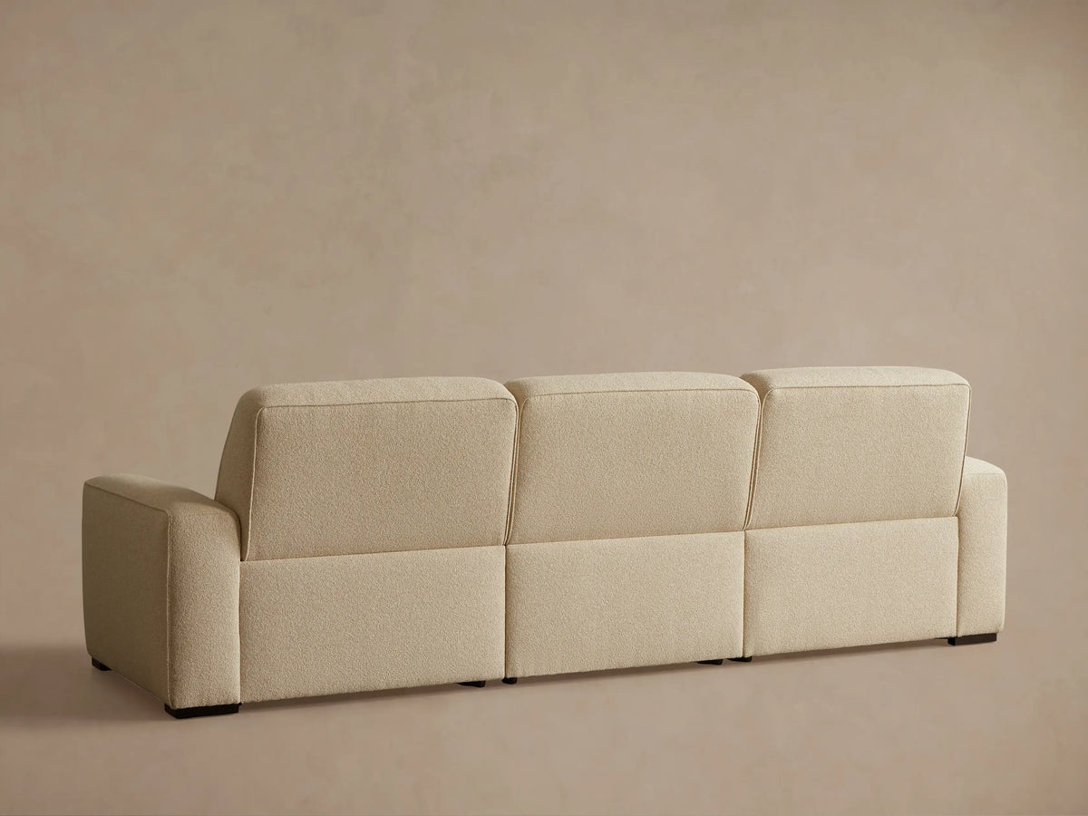 Close-up of the beige textured fabric and two dark oval motion control buttons on the Borough Three-Piece Motion Sofa.