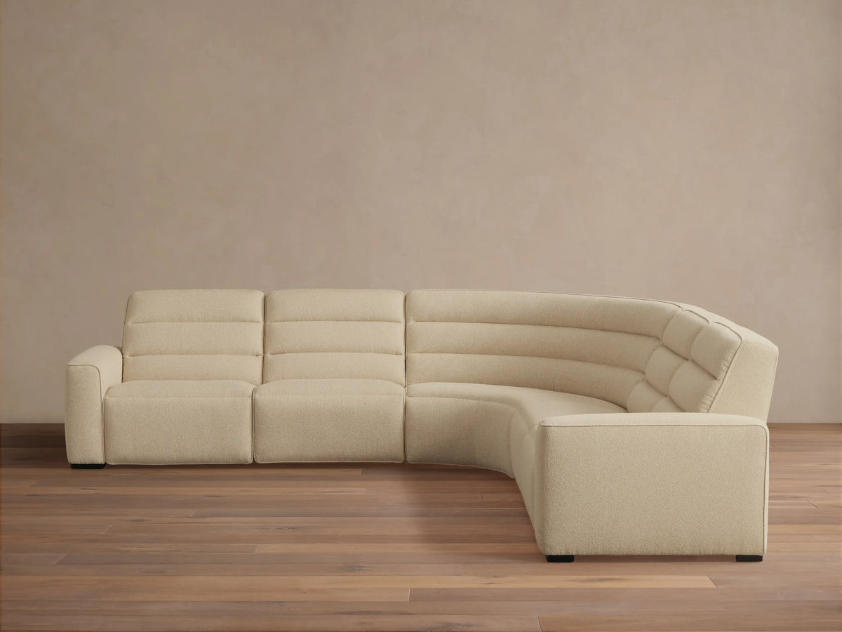 Front view of a cream Borough Five-Piece Motion Corner Sectional with horizontal ribbed recliners and a curved tufted corner.