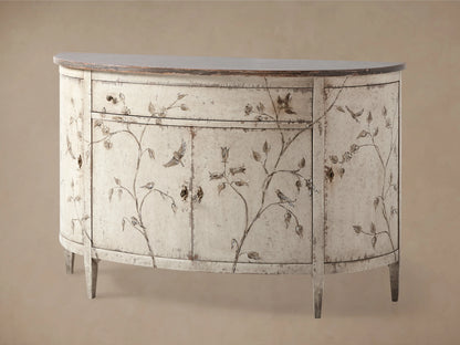 Sofia Bell'Arte Demilune Cabinet with a distressed antique finish, curved shape, and hand-painted bird and vine motifs on a wood surface.