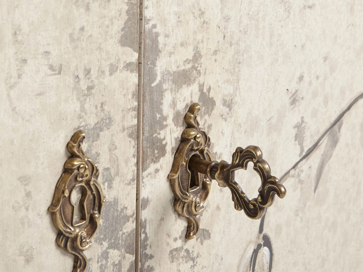 Sofia Bell'Arte Demilune Cabinet with cream finish, hand-painted bird and vine motifs, curved front, and tapered legs.