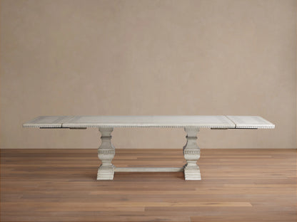 Distressed white Cerea Ribbon Bell'Arte Dining Table, hand-painted border, two pedestals, leaves partially extended.