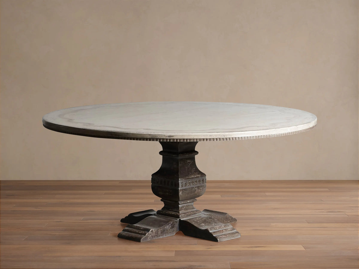Cerea Ribbon Bell'Arte Round Dining Table with light painted top, subtle ribbon border, and a dark ornate pedestal base.