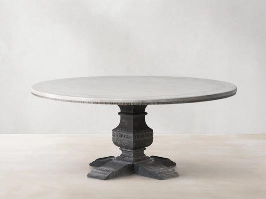Cerea Ribbon Bell'Arte Round Dining Table with light painted top, subtle ribbon border, and a dark ornate pedestal base.