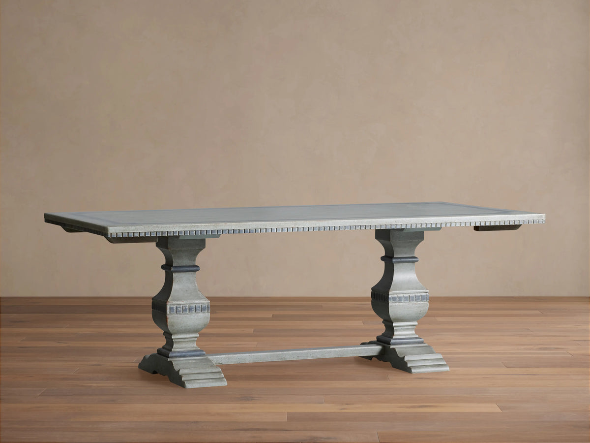 Cerea Gallery Bell'Arte Dining Table with distressed gray finish, rectangular top, two extensions, and carved double pedestal legs on wood floor.