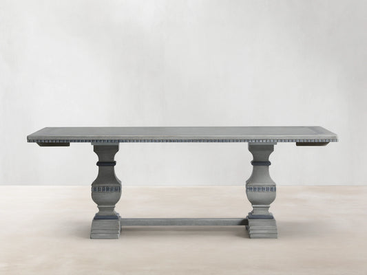 Cerea Gallery Bell'Arte Dining Table in distressed gray finish with ornate carved pedestal legs and rectangular top, on wood floor.