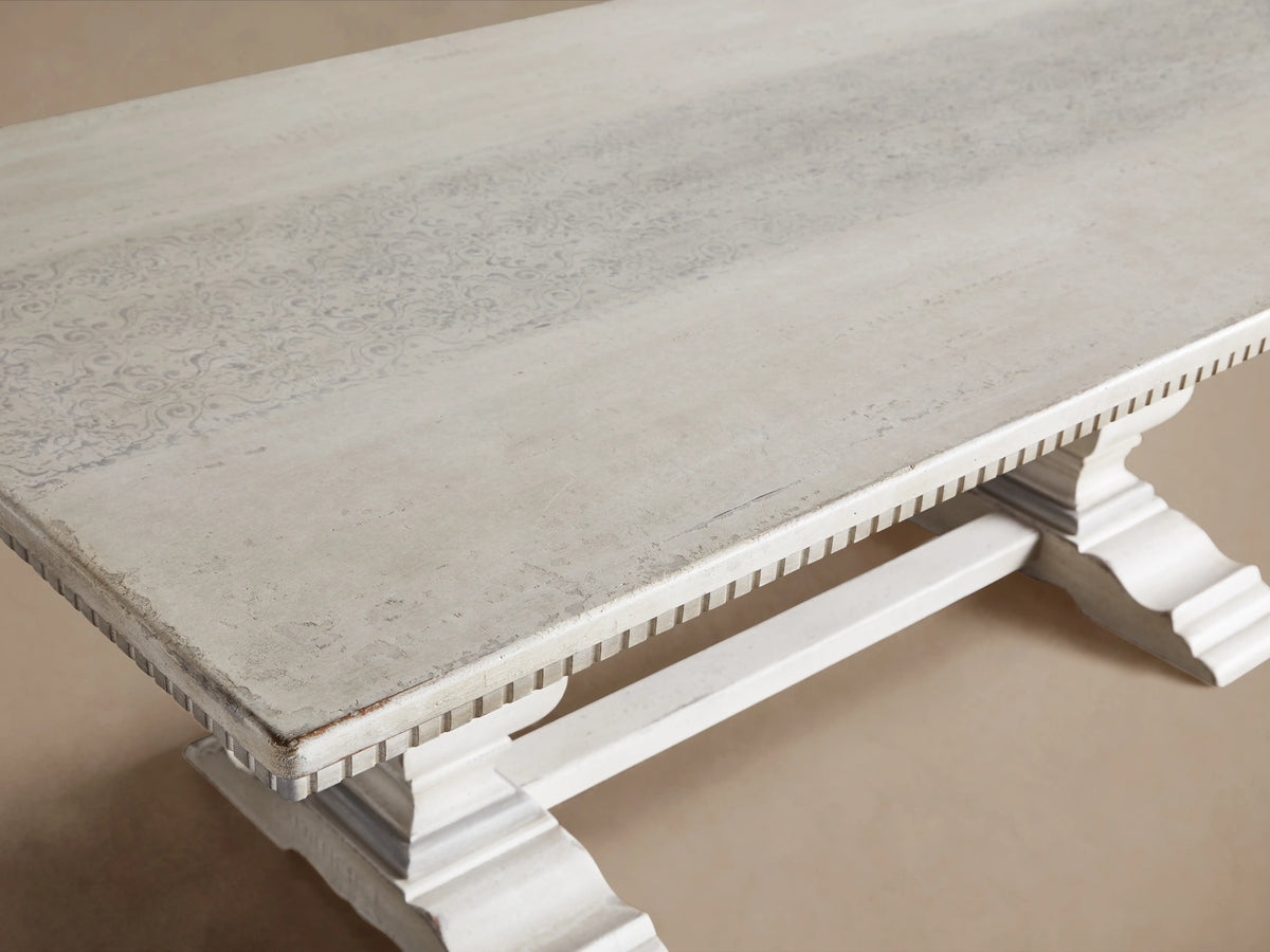 Cerea Amalfi Bell'Arte Dining Table in light finish with two 20" extensions, ornate pedestal legs, set on wooden floor indoors.