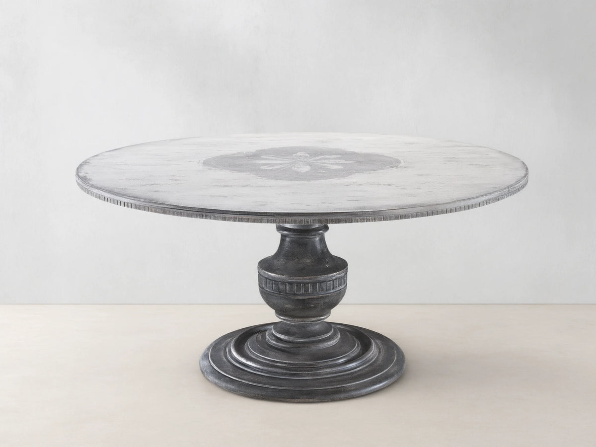 Florence Bell‚ÄôArte Round Dining Table. Distressed ivory grey top with central floral design, dark rust carved pedestal base.