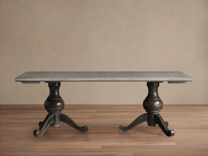 Girardi Geo Link Bell'Arte Dining Table featuring a long rectangular top in Antique White with an Antique Grey geometric border, supported by two ornate dark pedestal legs on a wooden floor.