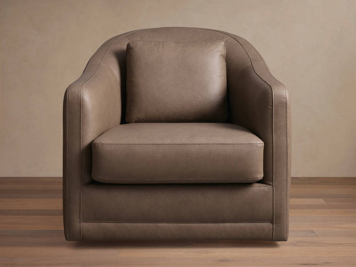 Front view of the Brown Bianca Leather Swivel Chair, featuring a curved back, integrated rounded arms, and a matching accent pillow.