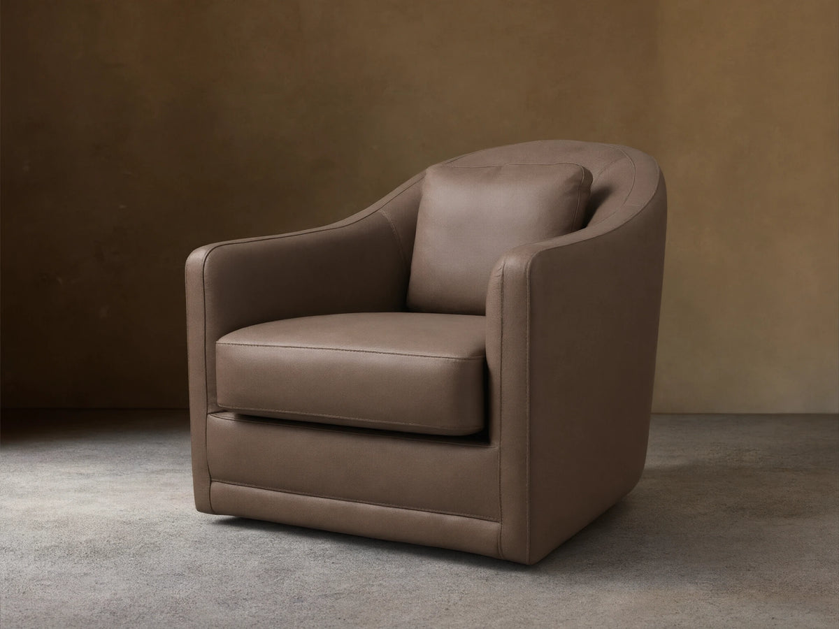 Front view of the Brown Bianca Leather Swivel Chair, featuring a curved back, integrated rounded arms, and a matching accent pillow.
