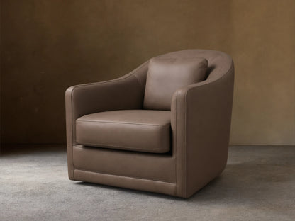 Front view of the Brown Bianca Leather Swivel Chair, featuring a curved back, integrated rounded arms, and a matching accent pillow.