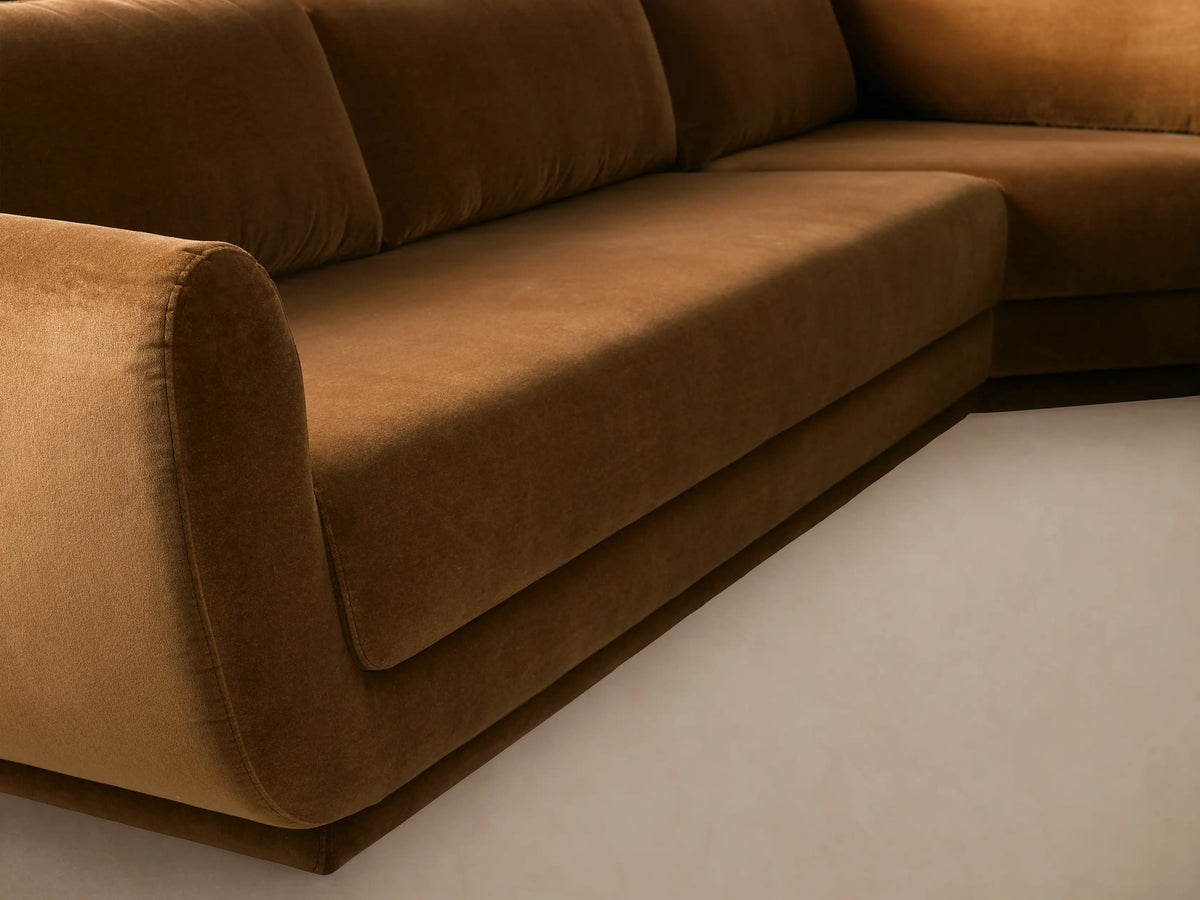 Fontana Three-Piece Corner Sectional, a large, L-shaped sofa in rich brown velvet, against a light wall & wood floor.