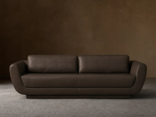 Front view of the charcoal grey Fontana Leather Sofa, with rounded arms, two plump back cushions, and a continuous plinth base.