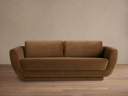 Front view of the brown Fontana Sofa, a two-seater with rounded arms, loose back cushions, and a low, solid base.
