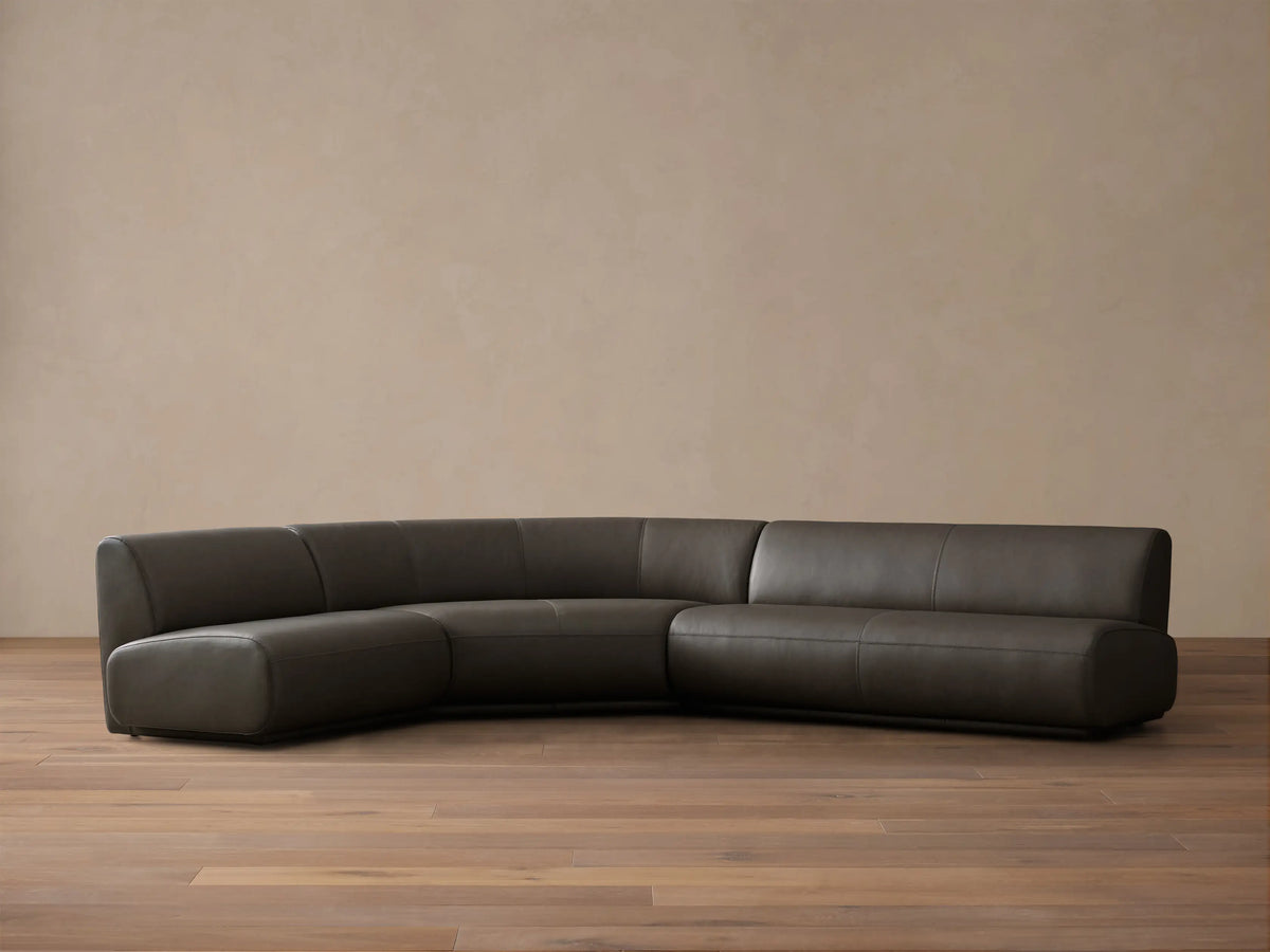 Front view of the Charcoal Gianni Leather Three-Piece Armless Bumper Sectional, featuring a curved corner and straight segments.