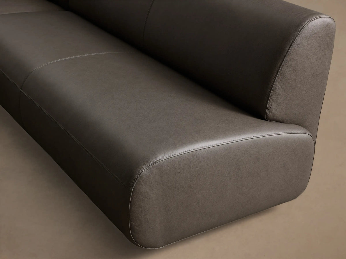 Front view of the charcoal Gianni Leather Three-Piece Armless Bumper Sectional, with soft L-shaped curves.