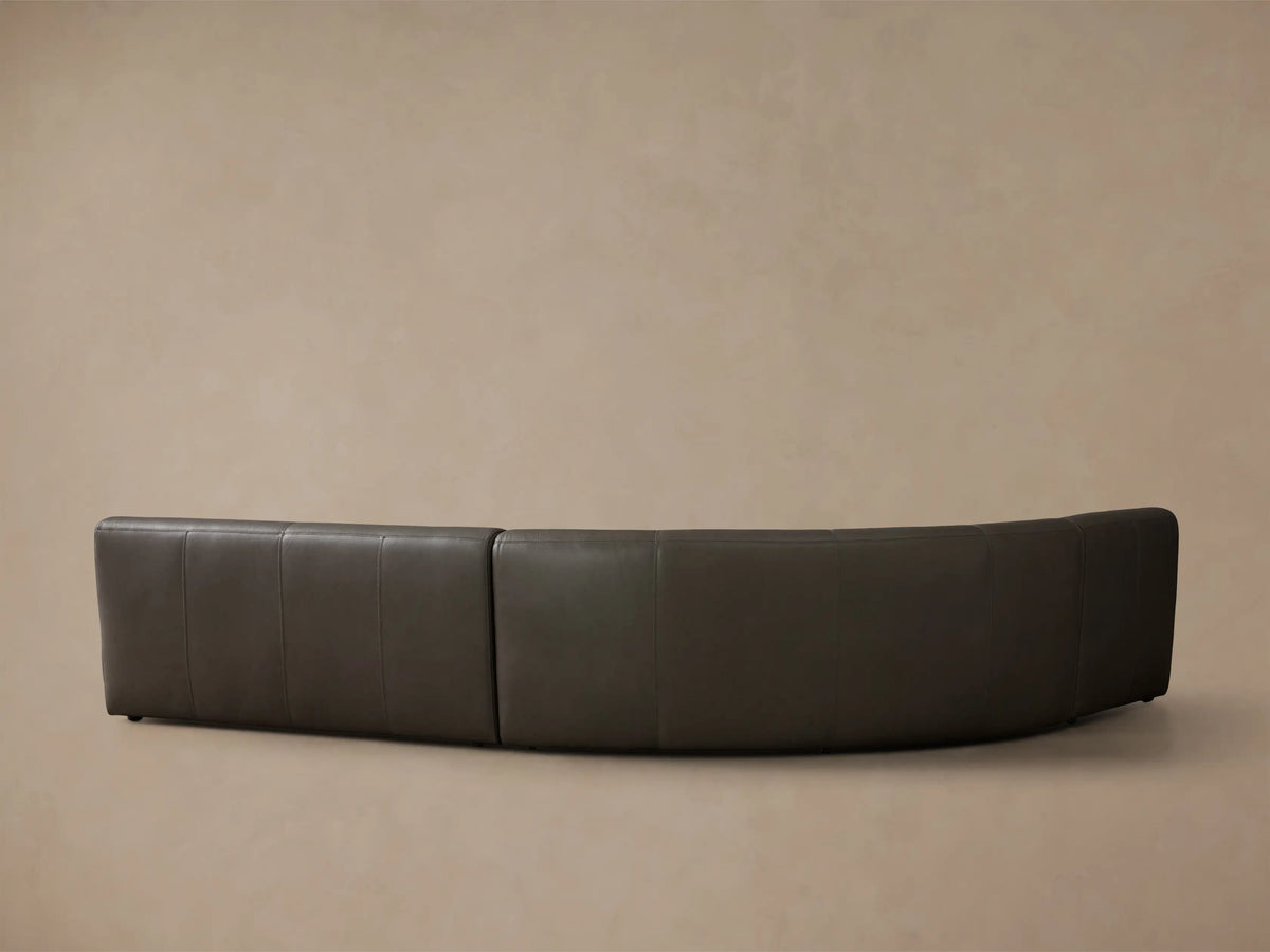 Close-up of the smooth dark taupe leather Gianni Leather Three-Piece Armless Bumper Sectional, showing seat and back with stitching.