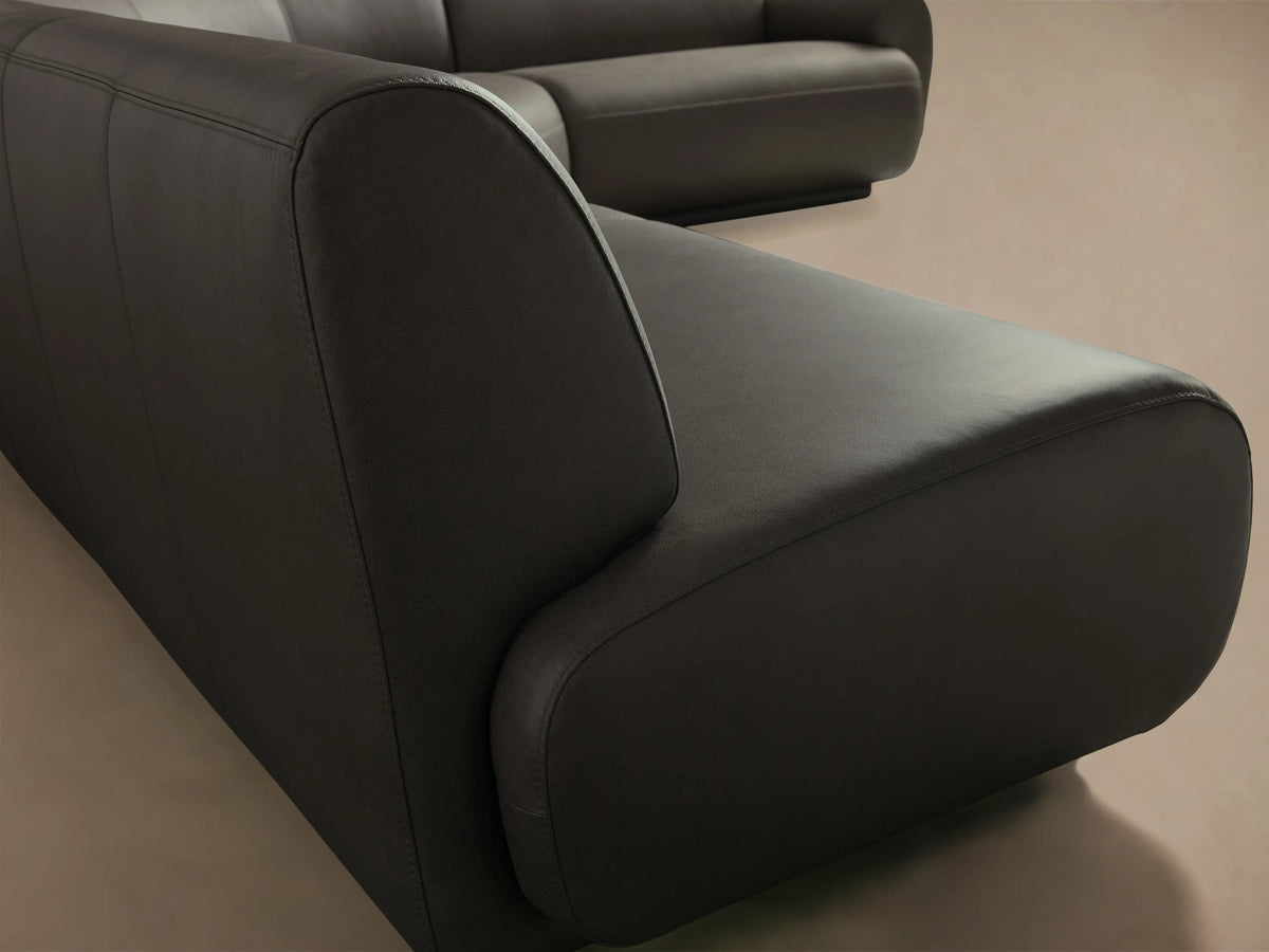 Front view of a dark gray Gianni Leather Three-Piece Sectional, with a curved design and low backrests.