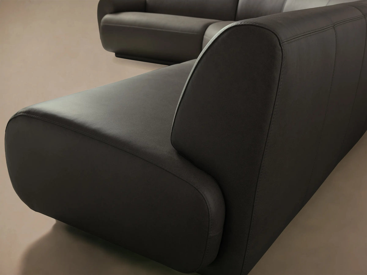 Close-up of the dark brown Gianni Leather Three-Piece Sectional, showcasing the smooth leather and rounded armrest with visible stitching.