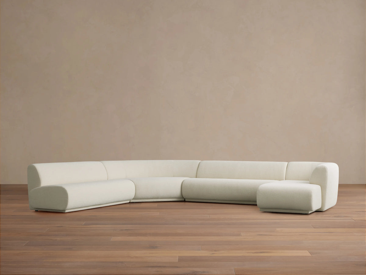 Cream Gianni Armless Four-Piece Chaise Sectional with rounded left corner, two center sections, and right chaise, on wood floor.