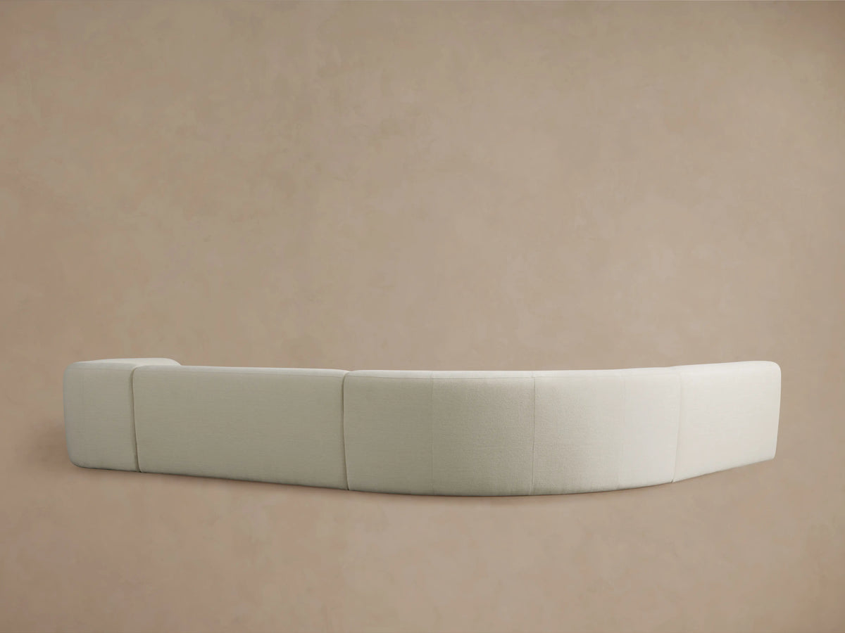 Close-up of Gianni Armless Chaise Sectional in textured light beige fabric, showing soft curves of the seat and rounded backrest.