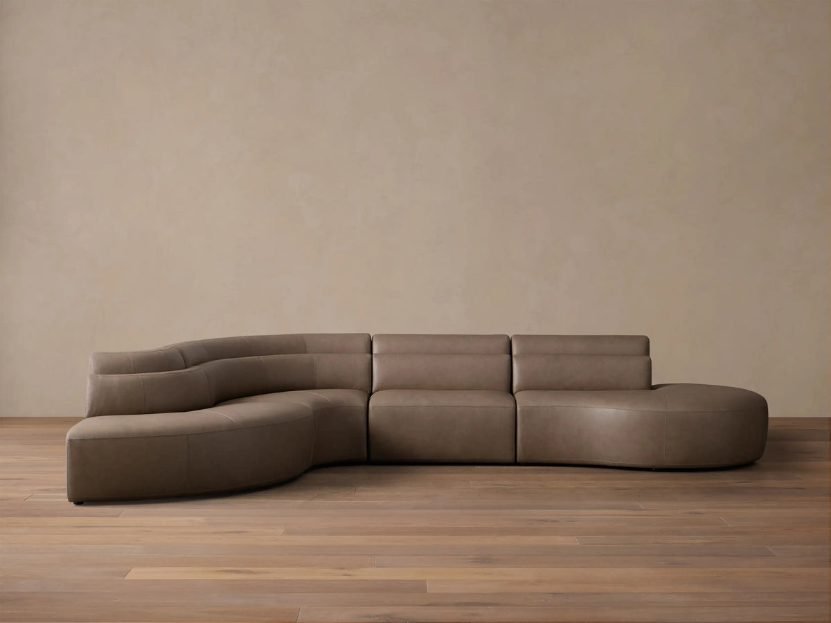 Front view of the taupe Lovina Leather Four-Piece Bumper Sectional, showcasing its sweeping modular curve.