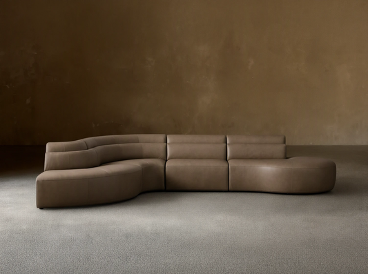 Front view of the taupe Lovina Leather Four-Piece Bumper Sectional, showcasing its sweeping modular curve.