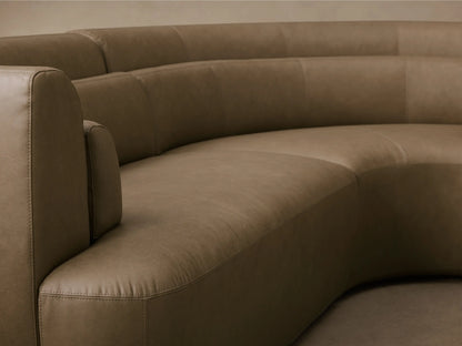 Front view of the curved olive green Lovina Leather Four-Piece Sectional with Ottoman, showing its soft leather and rounded shape.