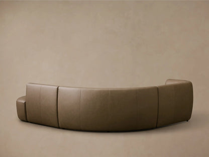 Close-up of a curved section of the Lovina Leather Four-Piece Sectional with Ottoman in taupe leather.