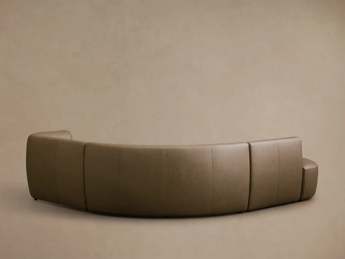 Front view of the olive brown Lovina Leather Four-Piece Sectional with Ottoman, showing its curved, modular design.