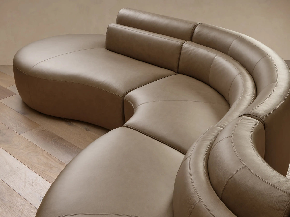 Angled top-down view of the taupe Lovina Leather Five-Piece Sectional, showcasing its smooth curved design and modular sections.