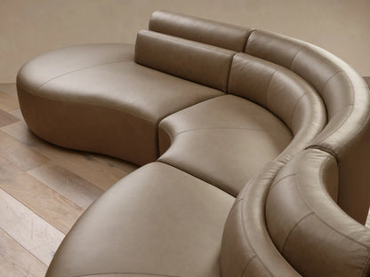 Angled top-down view of the taupe Lovina Leather Five-Piece Sectional, showcasing its smooth curved design and modular sections.